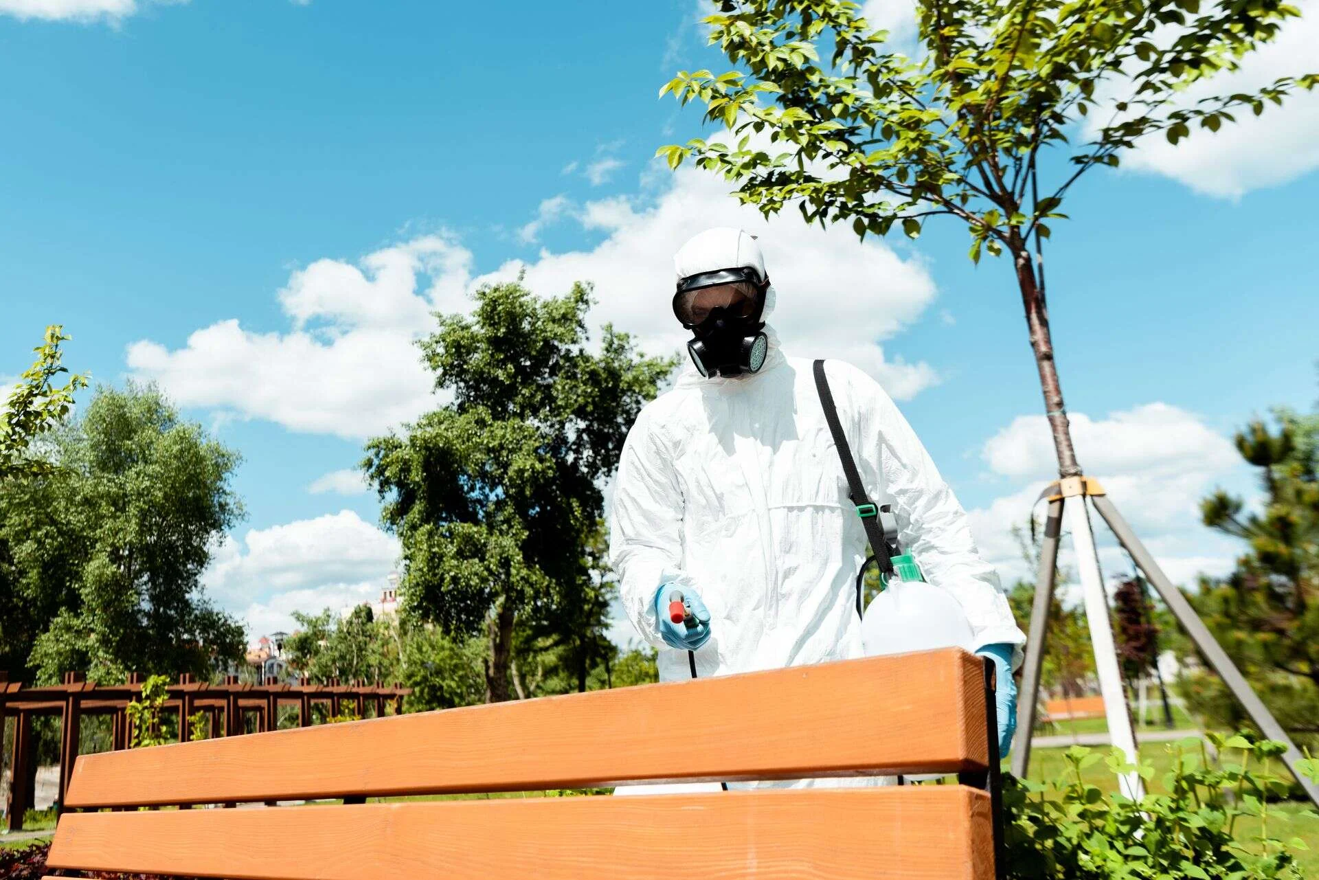 Técnico con equipo de protección aplicando tratamiento en una zona ajardinada